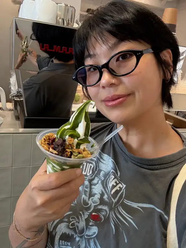 Jackie holding a matcha soft serve topped with granola and dried fruit
