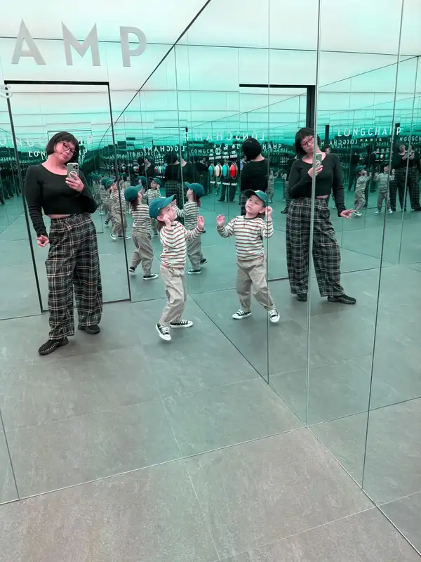 Jackie and a small boy reflected over and over in a mirrored room