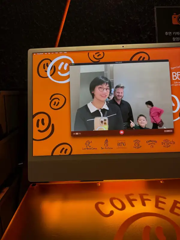 Jackie mid-pose with two other people on a coffee shop's photo booth screen